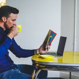 guy drinking coffee and looking at book