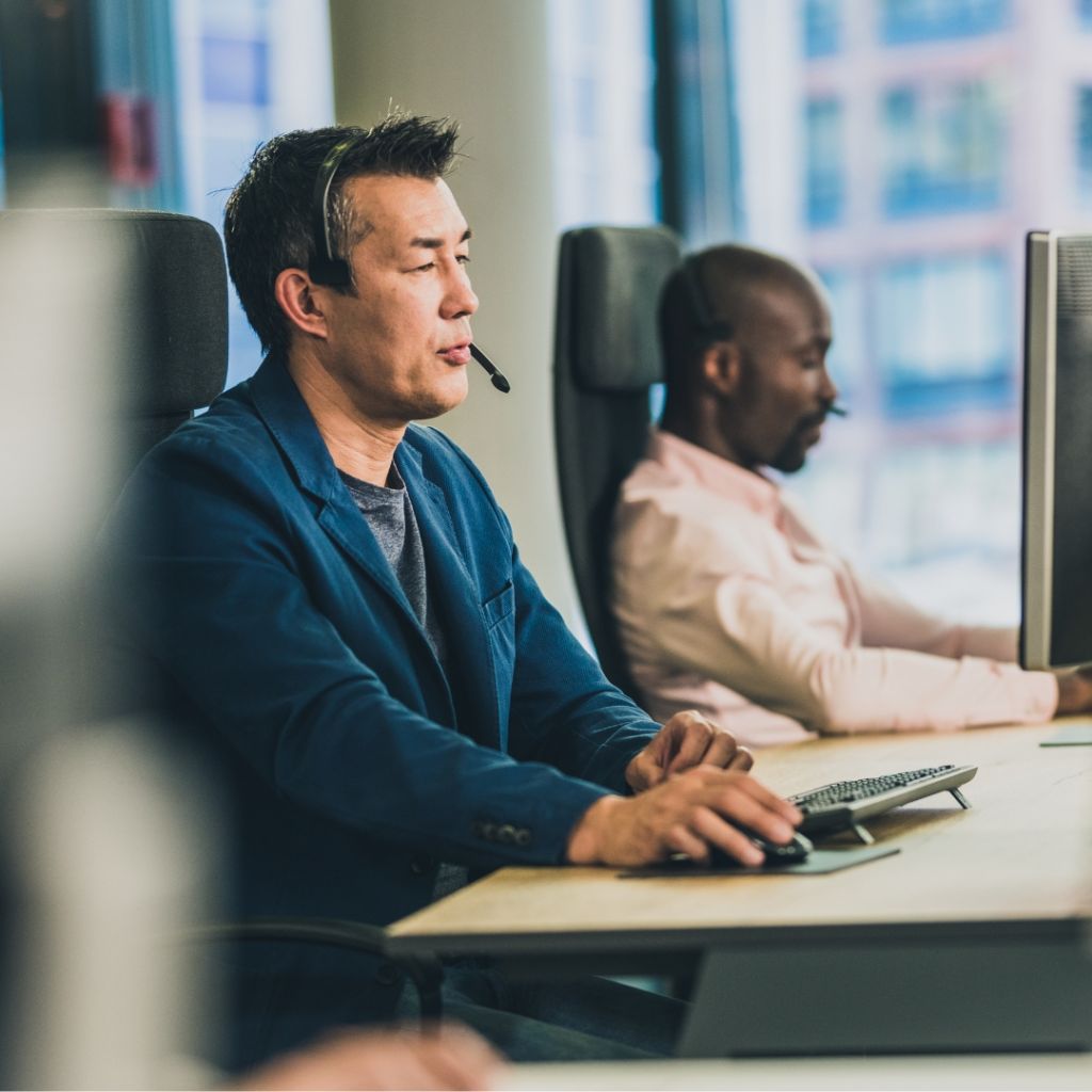 Two IT Professionals sitting at their desk, taking calls.