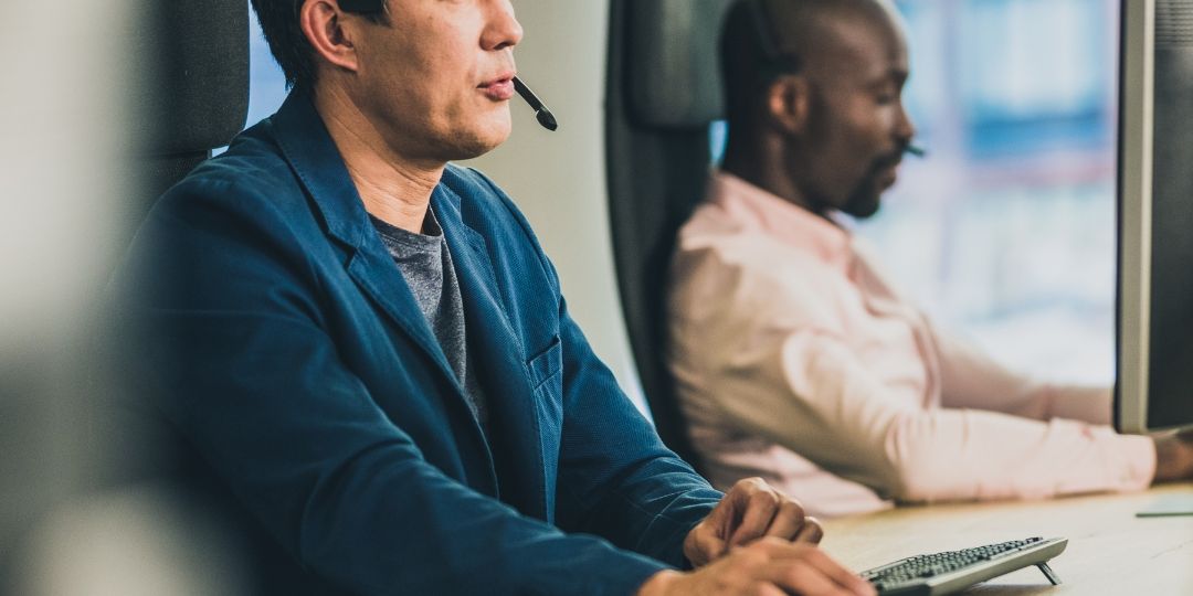 Two IT Professionals sitting at their desk, taking calls.